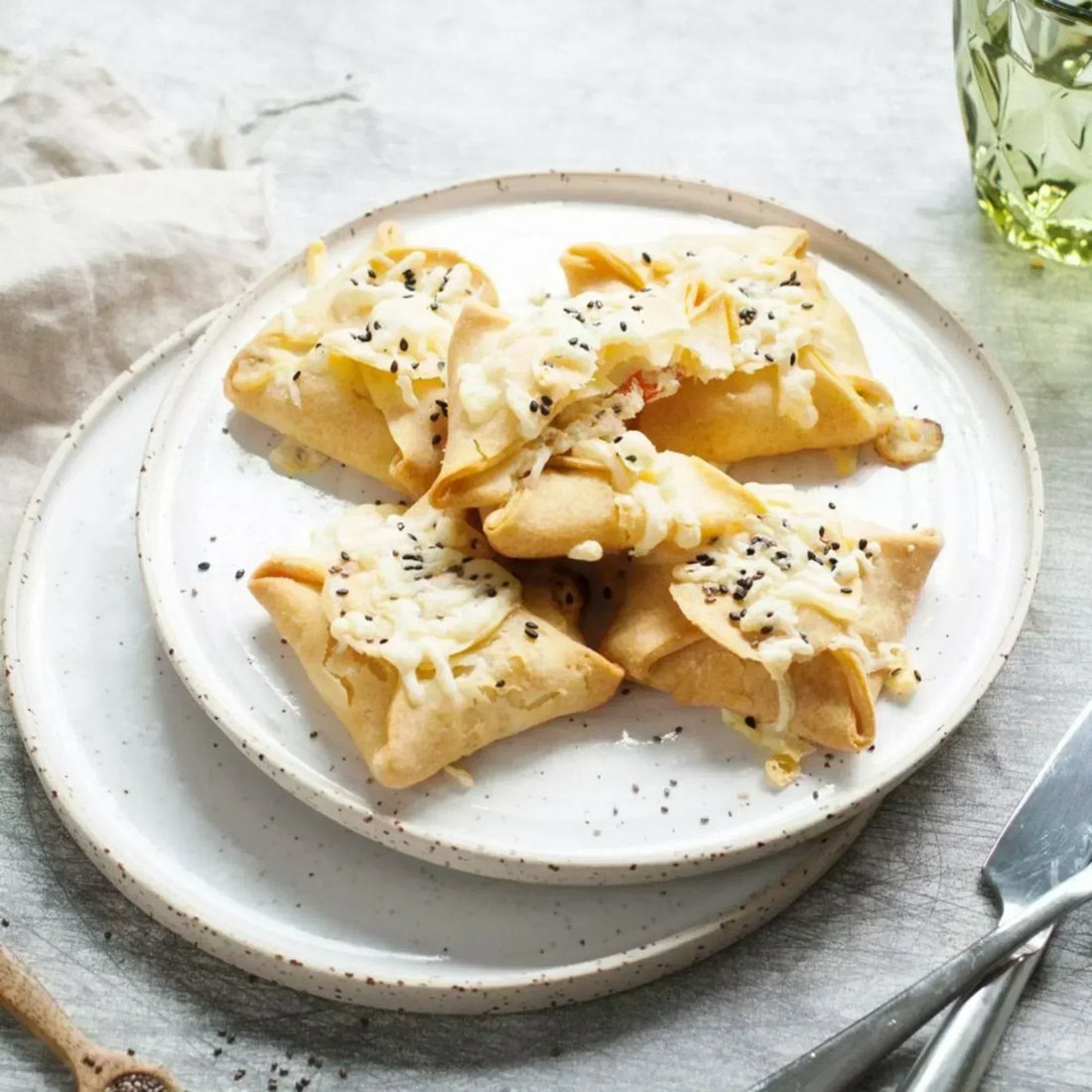 Goldbraun gebackene glutenfreie Teigtaschen, gefüllt mit Frischkäse, Kräutern und Paprika, angerichtet auf einem Teller.