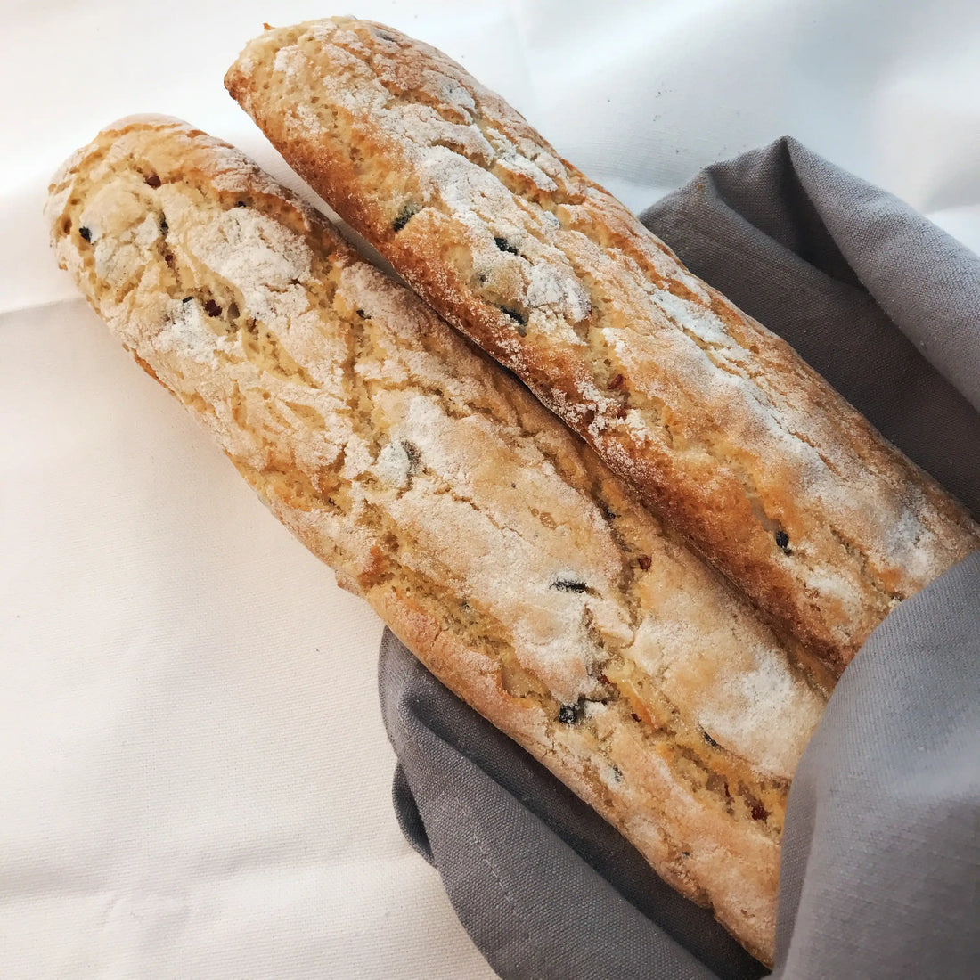 Glutenfreie mediterrane Baguettes mit knuspriger Kruste, belegt mit Oliven, getrockneten Tomaten und italienischen Kräutern.